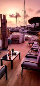 una terraza en la azotea con sillas, mesas y barcos en Marina Sunset, en Le Grau-du-Roi
