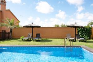 una piscina con sillas y sombrillas en Villa Marta Clara 2, en Conil de la Frontera