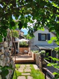 a backyard with a wooden deck with a table and chairs at Le Secret du Moulin, agréable tiny house Villefort in Villefort