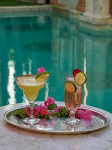 メリダにあるEl Palacito Secreto Luxury Boutique Hotel & Spaのプールサイドのトレイでのカクテル2杯