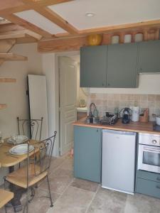 a kitchen with white cabinets and a table and a dining room at Le Secret du Moulin, agréable tiny house Villefort in Villefort