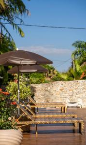 um banco com um guarda-sol, uma mesa e cadeiras em Pousada Villa das Pedras em Pirenópolis