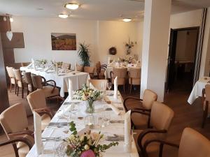 un restaurante con mesas blancas y sillas con flores. en Hotel-Restaurant Pfälzer Hof, en Edenkoben