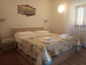 a bedroom with a bed with towels on it at Apartments Vodarić Loznati in Cres