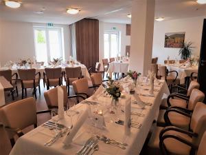 ein Zimmer mit Tischen und Stühlen mit weißen Tischdecken in der Unterkunft Hotel-Restaurant Pfälzer Hof in Edenkoben