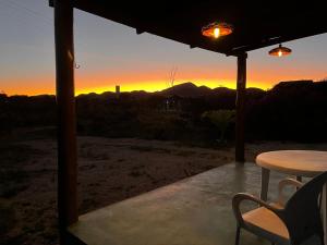 a table and chairs on a porch with a sunset at Chalé Uyuni in Alto Paraíso de Goiás