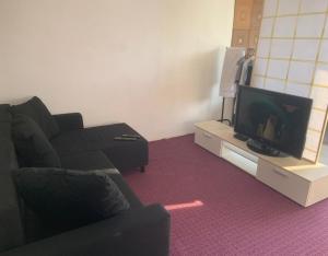 a living room with a black couch and a tv at Apartmány Blatec in Blatec