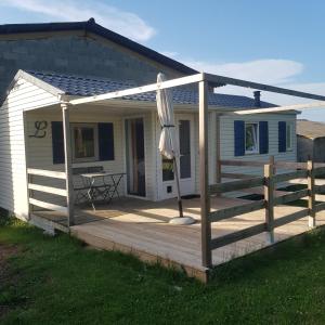 une maison avec une terrasse en bois et un parasol dans l'établissement accommodation à la ferme - appartement et mobilhome, à Lubersac