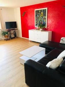 sala de estar con sofá negro y pared roja en Ferienwohnung Marie en Feldberg