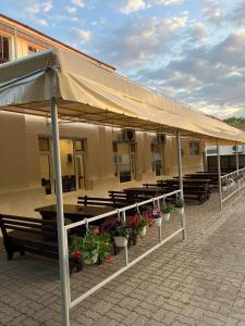 a building with benches and tables with flowers in front at Hostel Bistrița in Eforie Sud