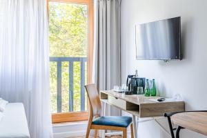 a desk in a room with a window and a table at Willa Letnia Apartamenty in Krynica Morska