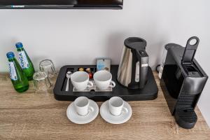 a black coffee maker with cups and saucers on a table at Willa Letnia in Krynica Morska +20 photos