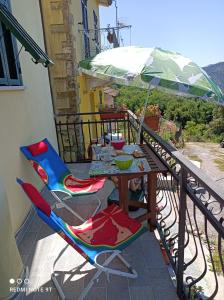 einen Tisch und Stühle auf einem Balkon mit Sonnenschirm in der Unterkunft La Quiete in Beverino
