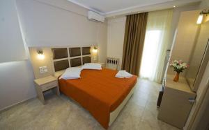 Gaia Studios & Apartments في نيا بلاجيا: غرفة نوم مع سرير برتقالي كبير في غرفة