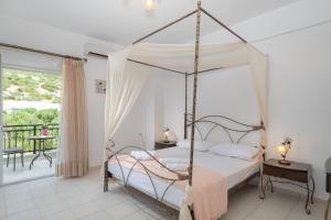 a bedroom with a four poster bed and a balcony at Haris Villas in Keratokampos