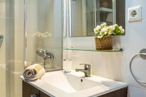 ein Badezimmer mit einem Waschbecken, einem Spiegel und Blumen in der Unterkunft Apartamento en la playa 105 in Guanarteme + 12 Fotos