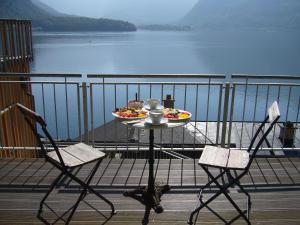 stół z 2 krzesłami i talerz jedzenia na balkonie w obiekcie Hallstatt Hideaway - Adults only w Hallstatt