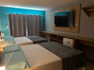 a hotel room with two beds and a flat screen tv at Pousada Paradise Vista do Atlantico in Maceió