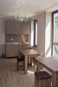 une cuisine avec des placards en bois, 2 tables et un lustre dans l'établissement Spitak tun, à Ijevan