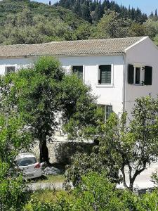 a white house with a car parked in front of it at George's house in Giannádes