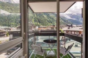 夏慕尼白朗峰的住宿－Le Petit Balcon avec vue sur le Mont-Blanc 2 étoiles，配有桌椅的房间的窗户享有风景。