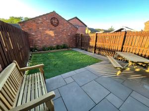 a backyard with two benches and a fence and grass at Tranquil 3 bedroom town house with Sky Glass in Thornton