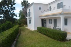 een wit huis met een groene heg bij Casa do Poco in Armação de Pêra