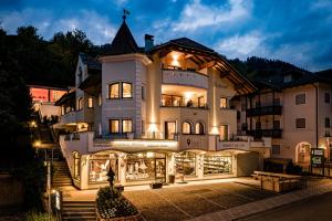 a large white building with a store front at night at Apartments Belaval in Santa Cristina Gherdëina