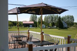 a patio with tables and chairs under an umbrella at Auberge Presbytere Mont Lac-Vert in Hébertville