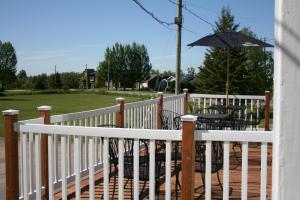 a white fence with tables and an umbrella on a deck at Auberge Presbytere Mont Lac-Vert in Hébertville