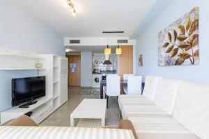 a living room with a white couch and a tv at Apartamento en Residencial Aldea Golf Panorámica in San Jorge