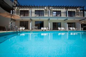 a large swimming pool with chairs and a building at Crystallo Apartments in Paphos