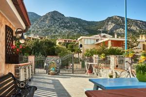a patio with tables and benches and mountains in the background at Villetta Vista Mare in Cala Gonone