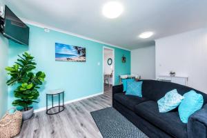 a living room with a black couch and a blue wall at Central Location - Noosa Address - Pet Friendly in Noosa Heads