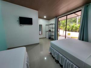 Hotel Casa Carlota Tamarindo في تاماريندو: غرفة نوم بسريرين وتلفزيون بشاشة مسطحة