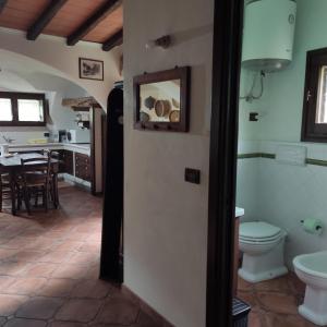 baño con aseo y cocina con mesa. en Casa Bados, en Dorgali