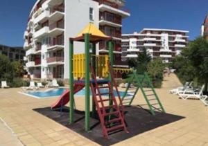 a playground with a ladder and a slide in front of a building at 2-комнатные апартаменты у моря 10 бассейнов Crown Fort Noks in Sveti Vlas