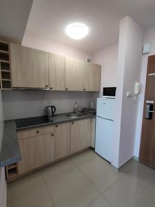 a kitchen with wooden cabinets and a white refrigerator at Apartament Alex in Mikołajki