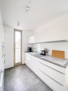 a white kitchen with white cabinets and a window at Strandläufer 2 in Zingst