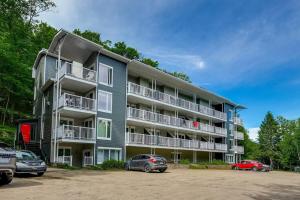 a large apartment building with cars parked in a parking lot at Studio LIV204 by Gestion ELITE in Mont-Tremblant