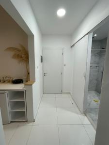 a bathroom with a shower and a white tile floor at Jz Plus e'Bella in Rhodes Town