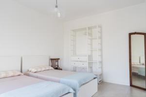 a white bedroom with two beds and a mirror at all'ombra del Bagolaro in Taglio di Po