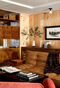 a living room with a leather couch and wooden walls at Bluebird Sunapee in Mount Sunapee