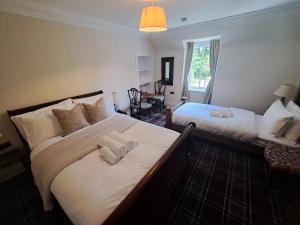 a bedroom with two beds with white sheets and a window at Clematis Cottage, Fortrose in Fortrose