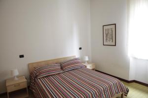 マリーナ・ディ・カッラーラにあるB&B Casa di Claudiaのベッドルーム1室(ストライプのベッドカバー付きのベッド1台、ナイトスタンド2台付)