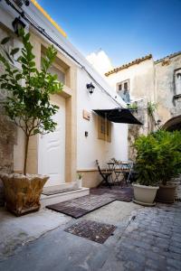 patio con porta bianca, tavolo e ombrellone di La Casetta del Ronco1 Ortigia a Siracusa