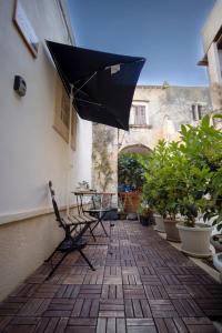 a patio with a table and a black umbrella at La Casetta del Ronco1 Ortigia in Siracusa