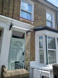 a house with a green door and windows at Bubblesbnb- 4 Bedroom House in London