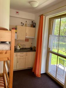 a small kitchen with an orange curtain and a window at Horský apartmán Prášily in Prášily