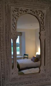 a mirror reflecting a bed in a bedroom at Fig Tree House in Penryn